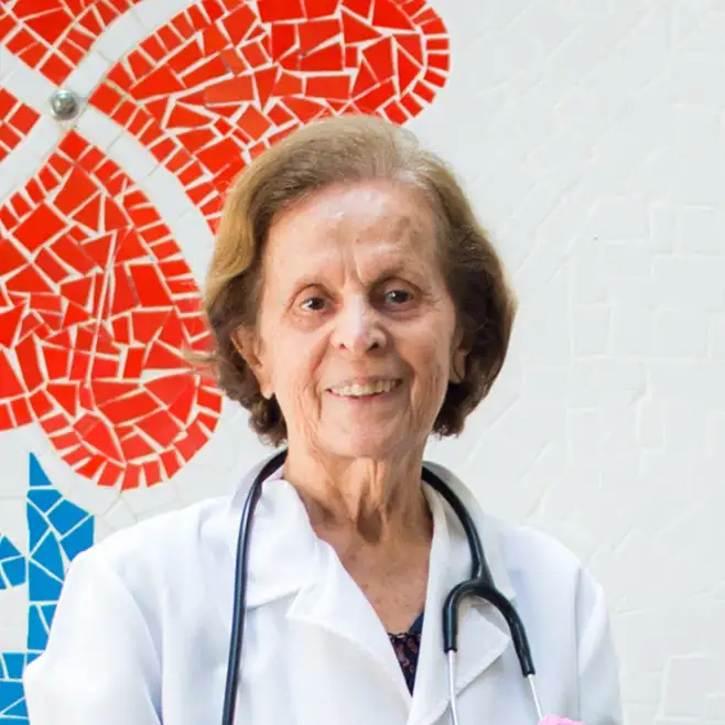 Doutora — imagem da campanha Dona Rosinha. (imagem 2) Senhora vestida de médica (jaleco e estetoscópio) em recorte com corações coloridos ao fundo.